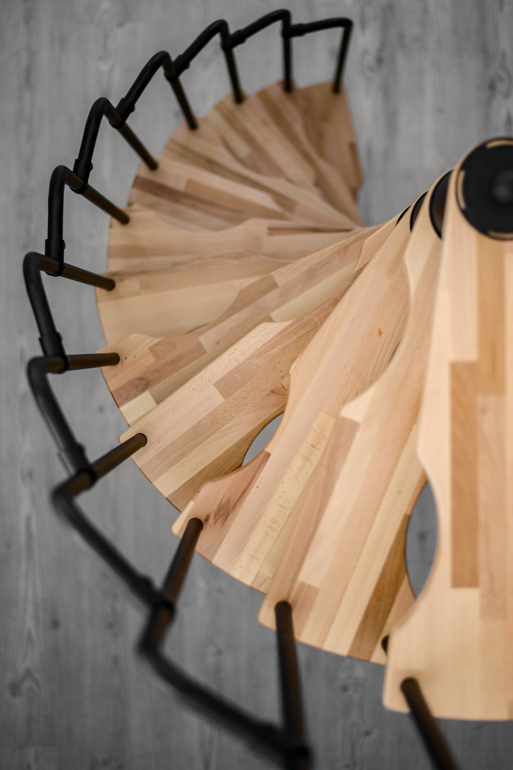Blick von oben auf die Spindeltreppe Suono. Die hellen Holzstufen und das schwarze Geländer verlaufen spiralförmig und unterstreichen das moderne, platzsparende Design.