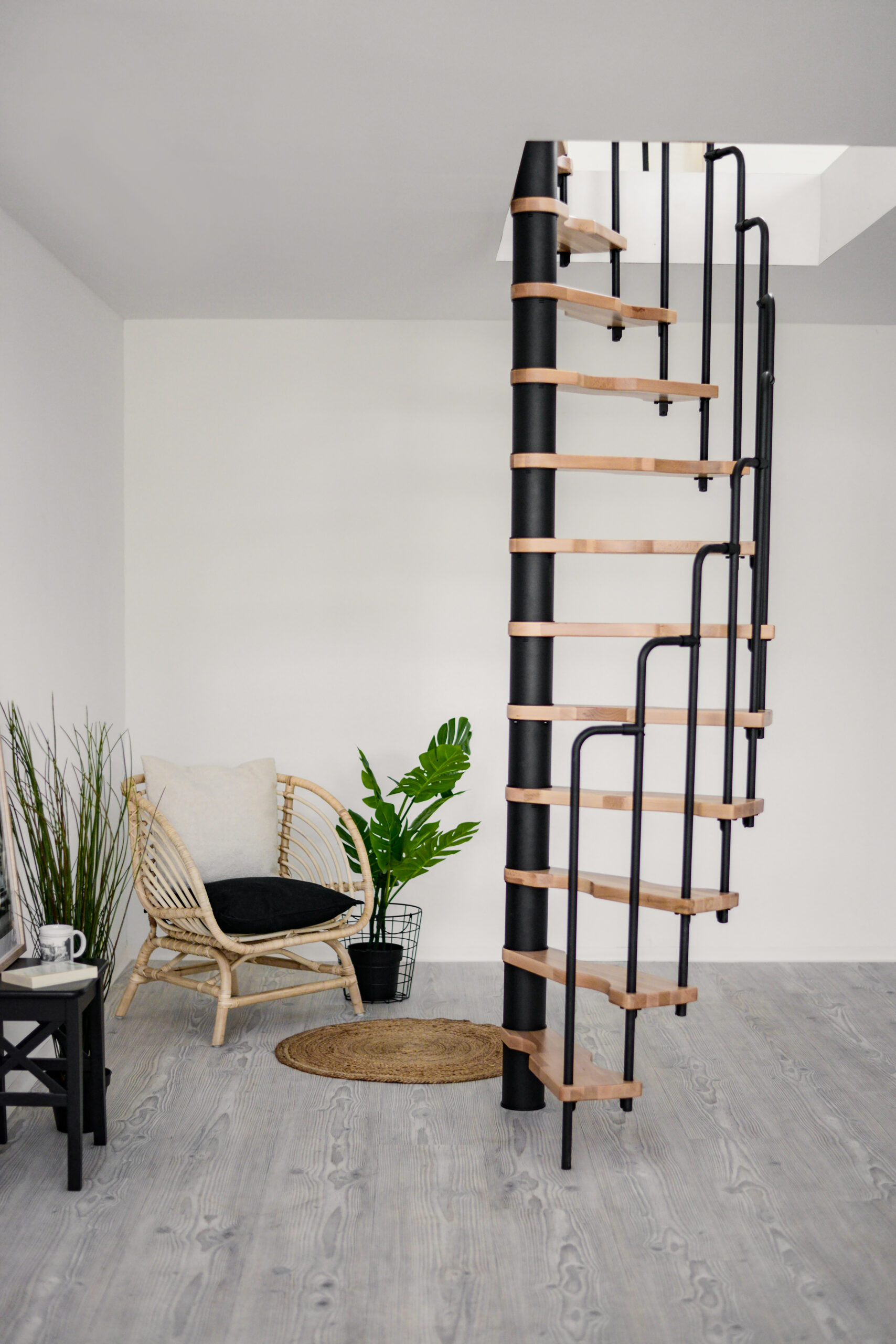 Die Spindeltreppe Suono überzeugt durch ihr minimalistisches Design mit schwarzem Mittelrohr, schwarzen Geländerstäben und hellen Holzstufen. Ideal für moderne und platzsparende Wohnkonzepte.