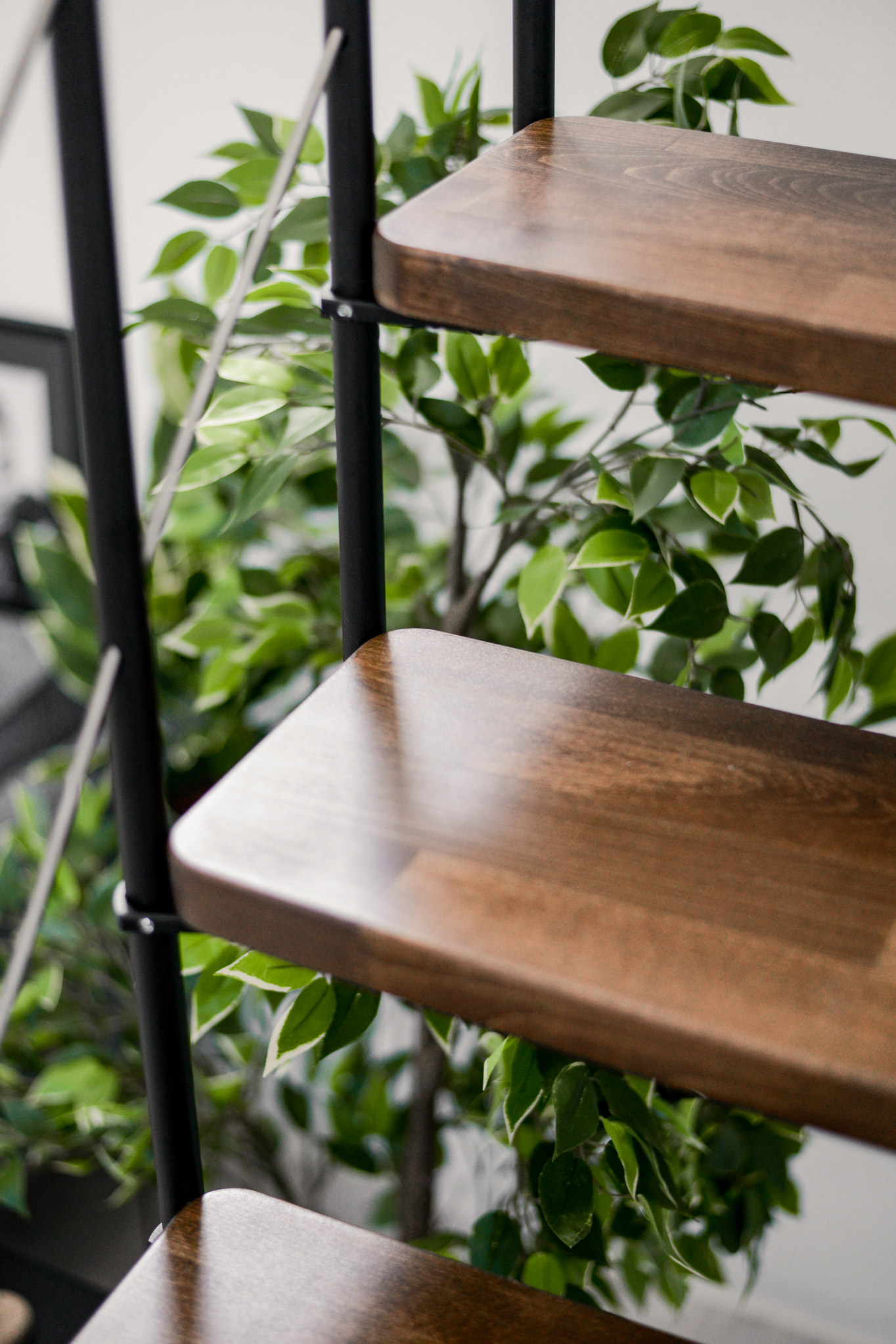 Nahaufnahme Comfort Top Turn Treppe im Schwarz-Walnuss-Design. Die dunkel gebeizten Holzstufen in Walnussoptik sind an einem schwarzen Metallgeländer befestigt.