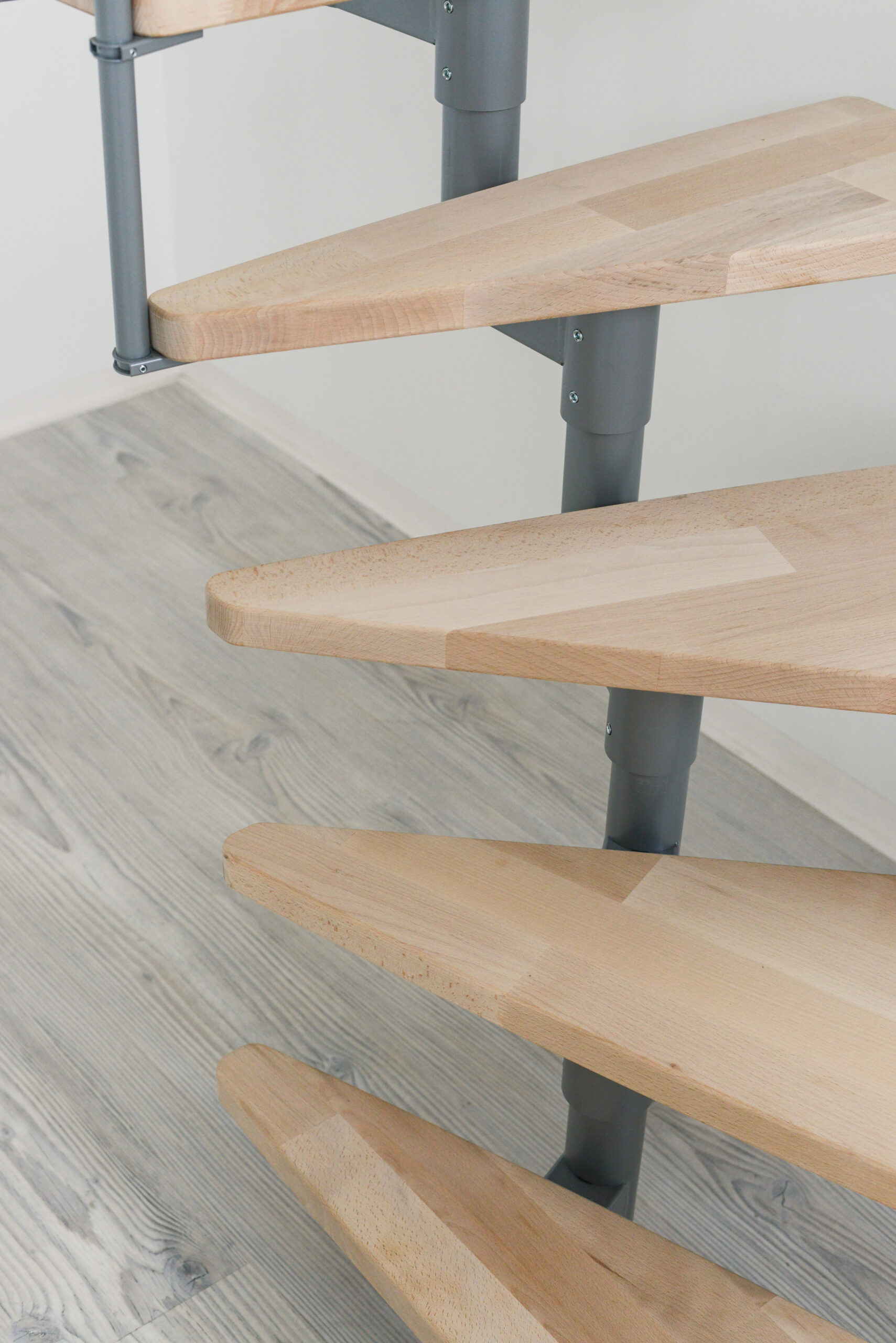 Nahaufnahme der Style Turn Treppe mit Walnuss-Stufen und einer grauen Metallkonstruktion. Die Stufen zeigen eine moderne, schwebende Optik, und die Wendung im unteren Teil sorgt für eine platzsparende Gestaltung.