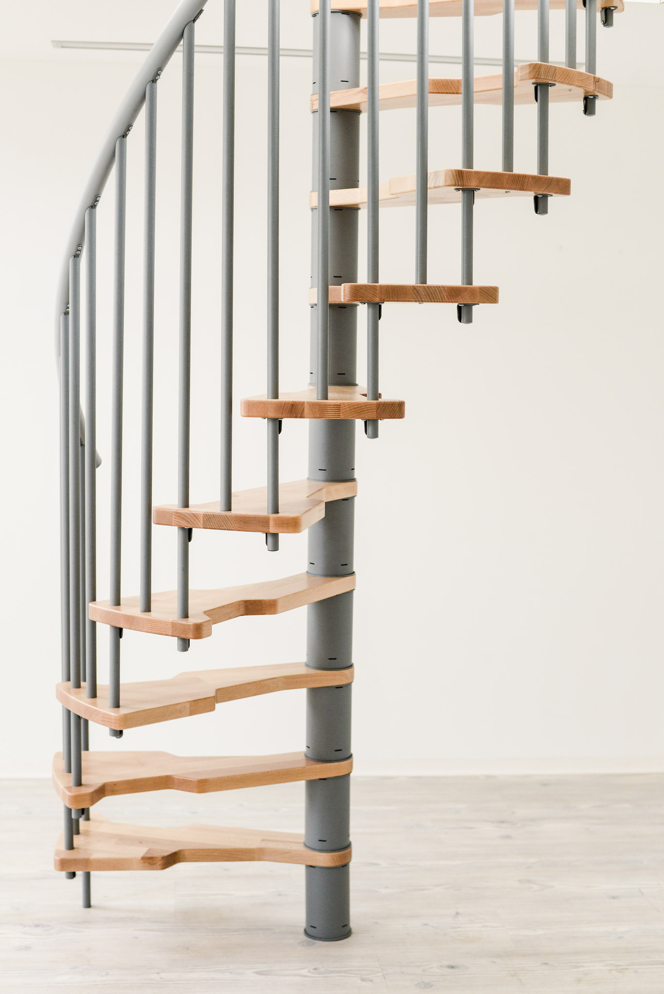 Seitenansicht der Spindeltreppe Metallica Smart. Die Kombination aus grauem Metallgestell und hellen Holzstufen sorgt für ein modernes und platzsparendes Design.