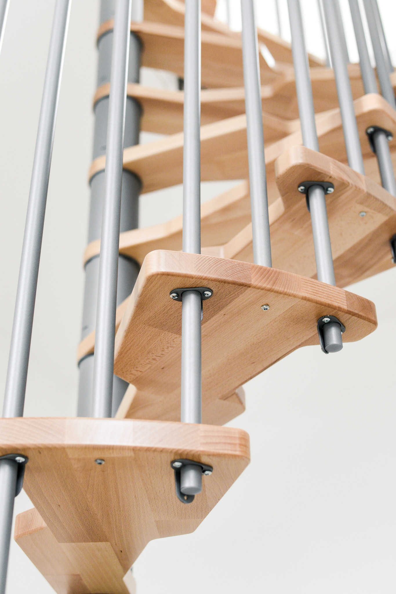 Nahaufnahme der Holzstufen und des grauen Geländers der Spindeltreppe Metallica Smart. Die stabile Konstruktion verbindet modernes Design mit hoher Sicherheit.