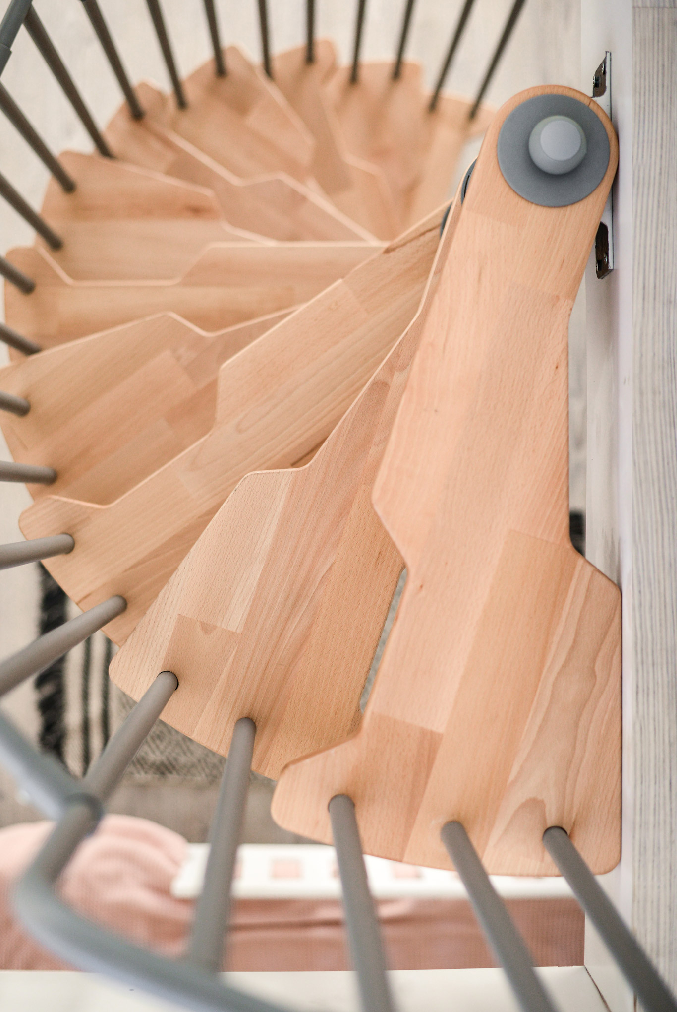 Blick von oben auf den Austritt der Spindeltreppe Metallica. Die hellen Holzstufen und das graue Geländer sorgen für ein sicheres und stilvolles Erreichen der oberen Ebene.