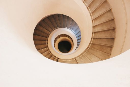 Helle Wendeltreppe mit Treppenauge in der Mitte von oben betrachet
