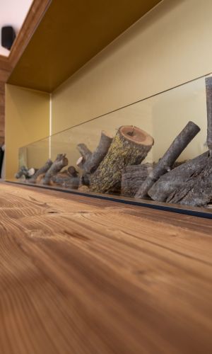 Detailaufnahme im Hotel Essigmanngut: stilvoller Innenbereich mit Wänden und Möbeln aus Azalea-Holz, gebürstet. Warme Maserung kombiniert mit modernen Elementen wie Glas und Kamin.