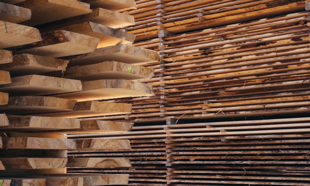 Gestapelte, naturbelassene Holzbretter und Holzstämme zur Weiterverarbeitung – Symbol für hochwertige Materialien.